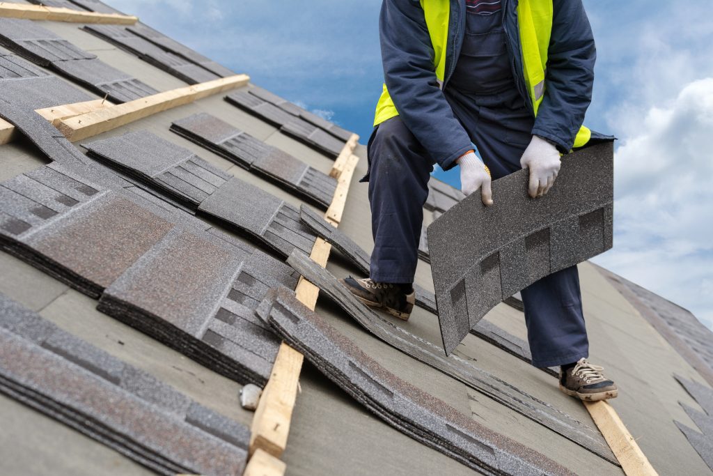 man on a roof placing shingles for a commercial roofing project