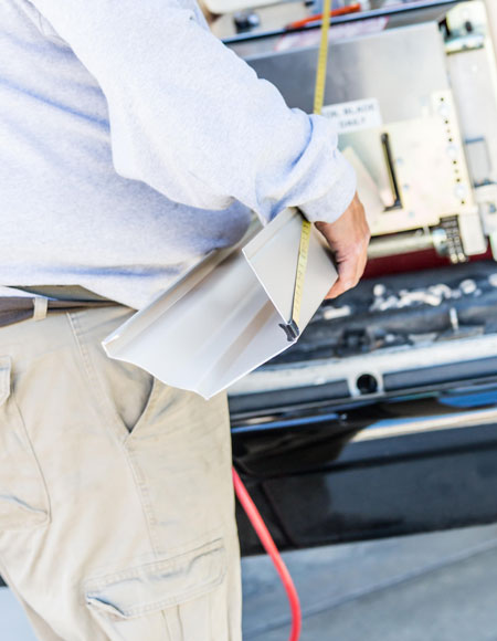 Person measuring and holding a section of residential gutter, preparing for installation, emphasizing gutter services by Nastase Contracting.