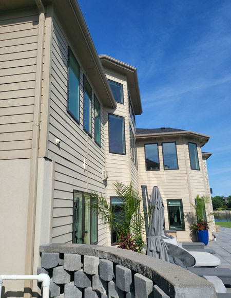 Residential siding installation on a modern home, showcasing beige siding, large windows, and a landscaped exterior in Omaha.