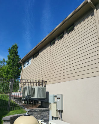 Residential home exterior showcasing beige siding, windows, and utility installations, emphasizing quality siding installation in Omaha.